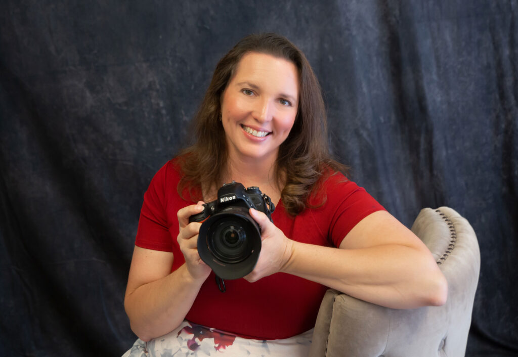 Photo of Shannon holding her Nikon camera smiling